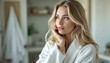 © Aimagination - Beautiful woman wearing a white bathrobe looking away from the camera with her hand on her face