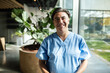 © Marko Geber - Smiling healthcare professional portrait in scrubs with arms crossed in hallway