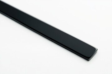 Poster - Close-up shot of a long black object on a white surface, great for product photography or design inspiration