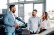 © Zamrznuti tonovi - Engaged couple conversing with car salesman in showroom.