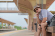 © reewungjunerr - Handsome young man with a backpack uses the phone while standing near the railroad train on the platform,Tourism and travel in the summer. Vacations for the student.
