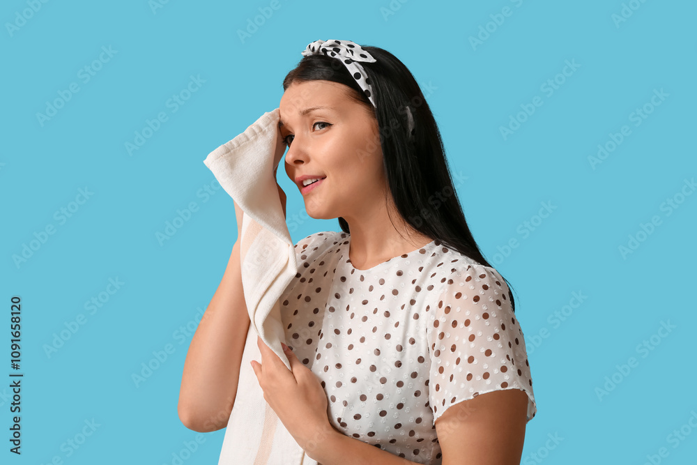 Tired young waitress with napkin on blue background