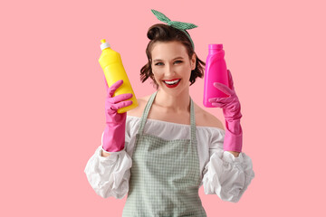 Wall Mural - Beautiful young happy pin-up housewife with bottles detergent on pink background