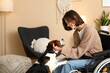 © Pixel-Shot - Young beautiful woman in wheelchair playing with cute Beagle dog at home