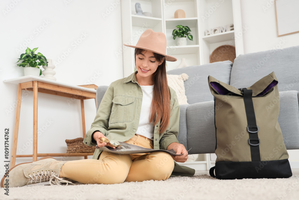 Female tourist with compass and map sitting on floor at home