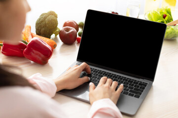 Aufkleber - Over the shoulder view of young female using personal computer with black empty screen for mock up design, checking email or browsing internet sitting at dinner table in kitchen, searching recipe