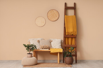 Interior of stylish living room with wooden bench, cushions and cozy blanket on ladder