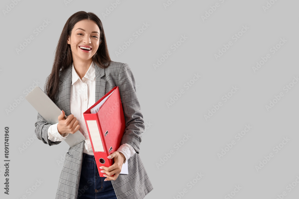 Beautiful businesswoman with folder and laptop on light background