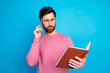 © deagreez - Thoughtful man in glasses holding a notebook and pen, contemplating ideas against a blue background
