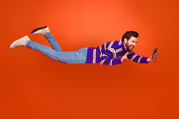 Poster - Full body photo of young man flying take selfie photo v-sign dressed stylish striped purple clothes isolated on orange color background