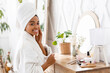 © Prostock-studio - Black Woman Sitting At Toilet Table And Touching Her Perfect Skin, Wrapped In Bathrobe And Towel Pampering Herself After Bath, Looking At Camera