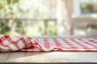 © raja - Red and white checkered tablecloth on a wooden table with a blurred background of a patio.