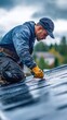 © EddieSnapix - A skilled roofer meticulously works on installing zinc roofing materials on a house. The worker is focused, wearing gloves and a cap, against a backdrop of cloudy autumn skies