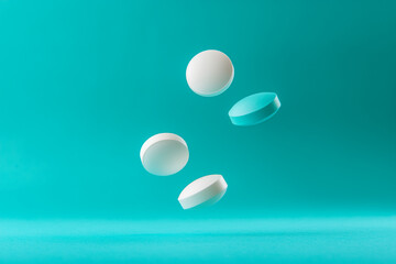 Poster - White and light blue pills falling on turquoise background
