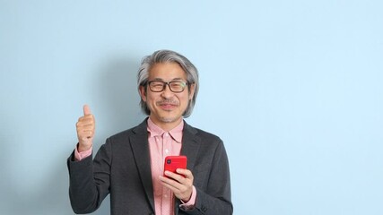 Wall Mural - The senior Asian man standing on the blue background.