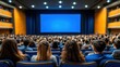 © Jakrapan - A crowded auditorium with an audience facing a blank blue screen, creating an atmosphere of anticipation for a presentation or performance.