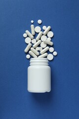 Wall Mural - Various pills pouring out of a medicine bottle on color background