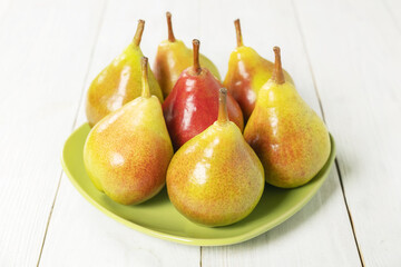 Wall Mural - Fresh pears in a ceramic plate on white wooden background