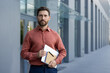 © Liubomir - Mature businessman with confident expression stands outdoors holding tablet and notebook. Dressed smart casual, he exudes professionalism and focus, representing modern urban work environment.