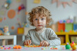 © Trissa - A toddler boy makes clay at a table in a kindergarten