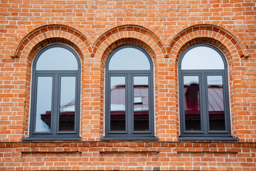 Wall Mural - The striking red brick building features three elegantly arched windows, enhancing its architectural style and contributing to its stunning visual appeal and unique character