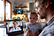 © Degimages - Father holding child in front of a laptop during a virtual consultation at home with a doctor