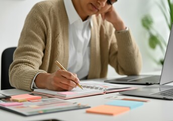 Poster - Focused businesswoman taking notes in her agenda and working on laptop in a modern office