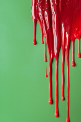 **Photograph of dripping red paint on a green , isolated against an green background. Minimal concept.