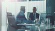 © Tingting - Business Professionals Engaged in Discussion Over Computer Screen in Office Conference Setting