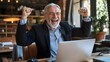 © MINA - Overjoyed Senior Businessman Celebrates Promotion and Salary Increase After Receiving Bonus and Recognition for Achieving Important Corporate Goal on His Laptop