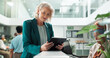 © peopleimages.com - Business, typing and mature woman with tablet, reception and network with internet, connection and social media. Person, consulting agency and employee in workplace, tech and welcome with digital app