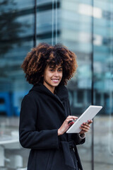 Wall Mural - young African American business woman using digital tablet in city of Spain Europe, financial and caribbean people with skyscraper background