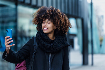 Wall Mural - young African American business woman talking and using mobile phone in city of Spain Europe, financial and caribbean people with skyscraper background	