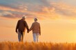 © Vilaysack - An elderly couple holding hands and walking through a wheat field at sunset, bathed in warm golden light under a vibrant sky.
