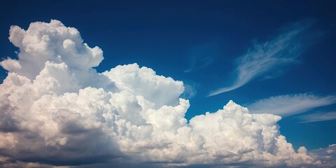 a dramatic blue sky with towering, cumulus clouds that stretch high into the atmosphere, mountainous
