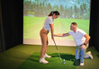 © Nadzeya - A golf instructor provides personalized guidance to a student in a high-tech indoor training facility