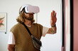 © AnnaStills - Man immersed in virtual reality experience wearing white headset and interacting with art on wall