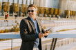 © BGStock72 - Professional man using tablet outdoors in a modern urban setting during golden hour light