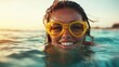 ©  Shomixer - A cheerful woman wearing large yellow goggles is captured in the ocean, enjoying a sunny day, highlighting themes of playfulness and freedom in nature.