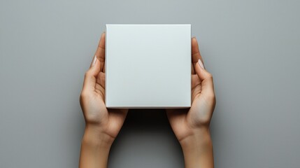 Poster - Two Hands Holding a White Square Box on a Grey Background