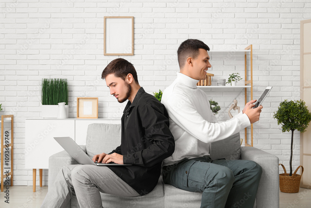 Young men using gadgets on online date at home