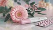 © lastfurianec - The photo shows a close-up of a pregnancy test, a package of birth control pills, a gerber daisy, green leaves and a marble surface. The image is intended to be a choice in a woman's life.