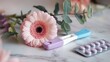 © lastfurianec - The photo shows a close-up of a pregnancy test, a package of birth control pills, a gerber daisy, green leaves and a marble surface. The image is intended to be a choice in a woman's life.