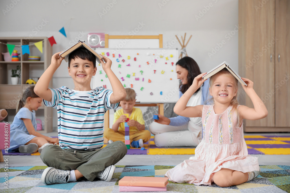 Funny little children with books sitting in kindergarten