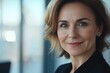 © Nognapas - Close-up headshot of confident European mature, good looking middle-aged leader, businesswoman CEO on blurred office background. Beautiful senior European businessman smiling at the camera