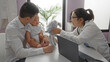 © Krakenimages.com - Father with baby boy at clinic interacting with female pediatrician showing a toy, highlighting family love in a welcoming hospital room.