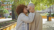 © Krakenimages.com - Interracial couple kissing passionately in an urban park with trees and street in the background.
