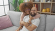 © Krakenimages.com - Interracial couple smiling together on grey sofa in a cozy living room