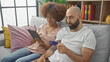 © Krakenimages.com - Interracial couple shopping online together using a tablet and credit card in a cozy living room.