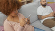 © Krakenimages.com - A woman and man sitting on a couch, both focused on their smartphones in a home environment.